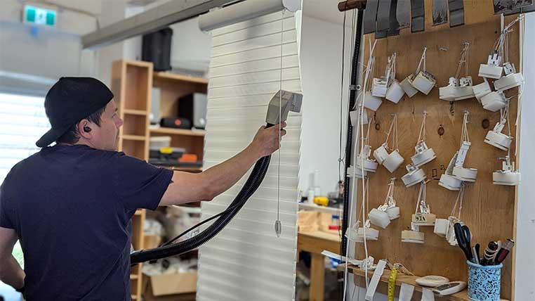 Workman cleaning hanging blinds